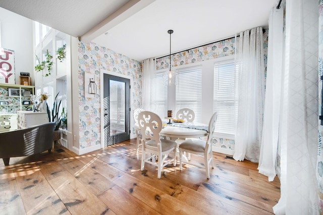 dining space with hardwood / wood-style floors, a wealth of natural light, and beamed ceiling