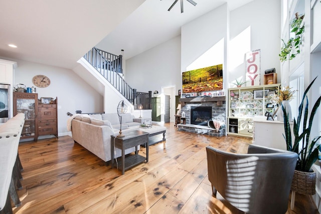 living room with a towering ceiling, hardwood / wood-style floors, and a fireplace