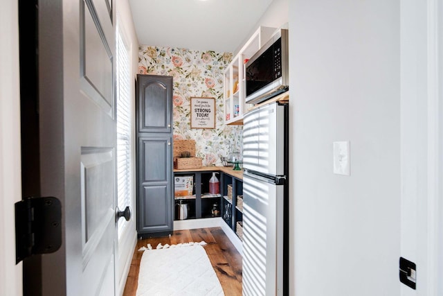 kitchen with gray cabinets, appliances with stainless steel finishes, butcher block counters, beverage cooler, and light hardwood / wood-style flooring