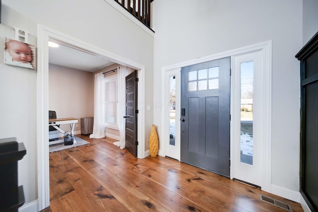 entryway with a towering ceiling and hardwood / wood-style floors