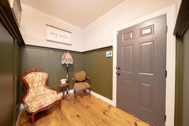 sitting room featuring lofted ceiling, wood-type flooring, and a textured ceiling