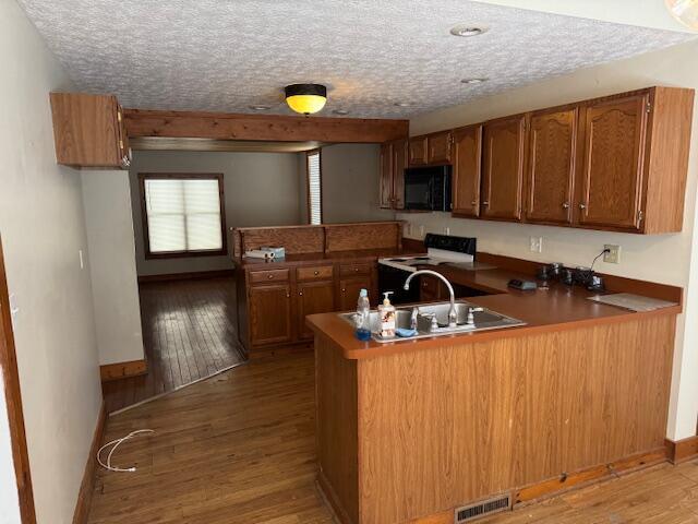 kitchen featuring hardwood / wood-style flooring, a textured ceiling, white electric range oven, and kitchen peninsula