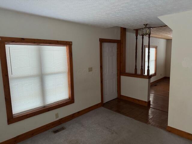 carpeted empty room featuring a textured ceiling