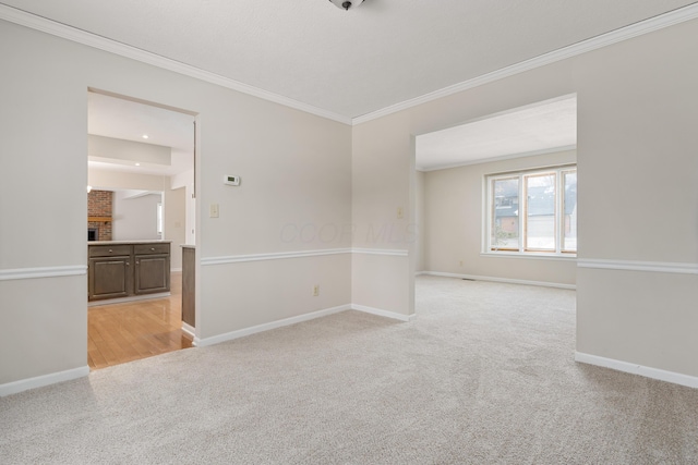 empty room featuring ornamental molding, a fireplace, and light carpet