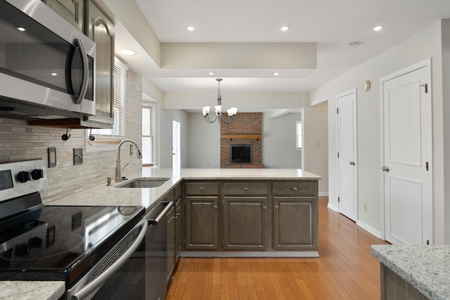 kitchen with dark brown cabinetry, sink, tasteful backsplash, light hardwood / wood-style flooring, and stainless steel appliances