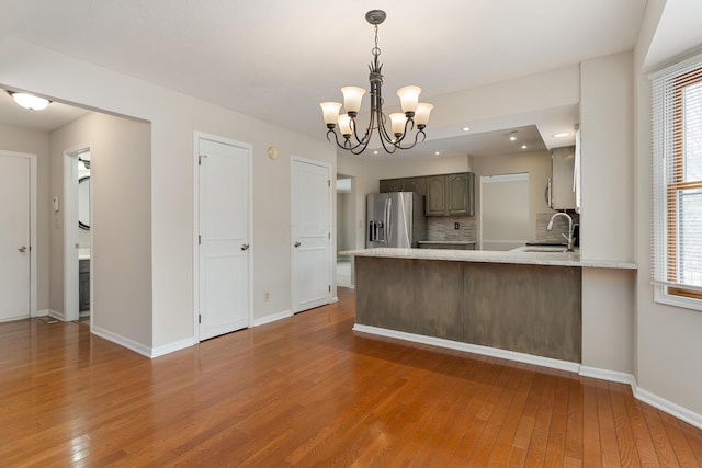 kitchen featuring sink, tasteful backsplash, wood-type flooring, stainless steel fridge with ice dispenser, and kitchen peninsula