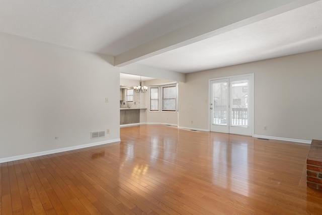 unfurnished living room with beam ceiling, light hardwood / wood-style flooring, and a chandelier