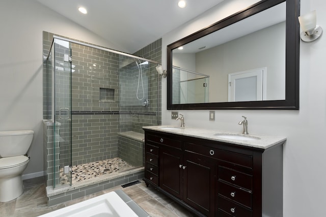 bathroom with vanity, toilet, a shower with door, and vaulted ceiling