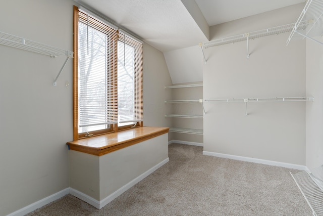 walk in closet with lofted ceiling and light colored carpet