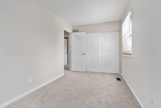 unfurnished bedroom featuring light colored carpet and a closet