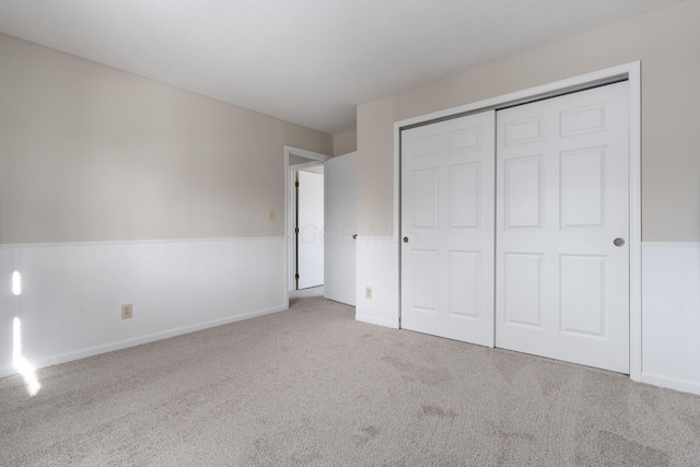 unfurnished bedroom with light carpet and a closet