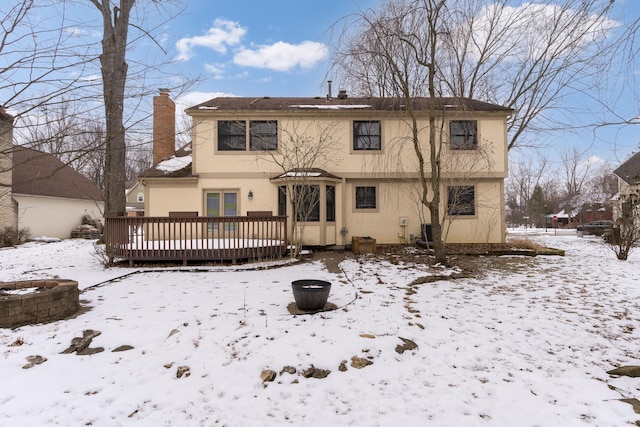 snow covered rear of property featuring a deck, central air condition unit, and an outdoor fire pit