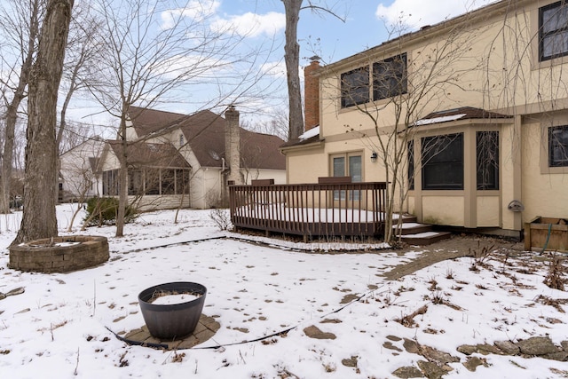 snow covered back of property with a wooden deck