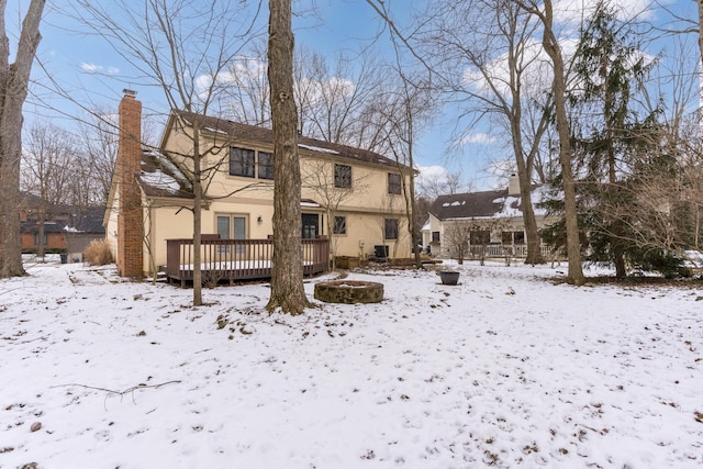 snow covered property featuring a wooden deck and an outdoor fire pit