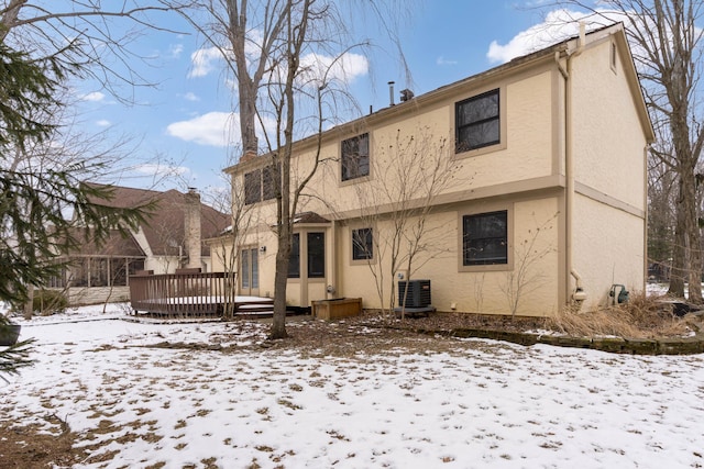 snow covered house with a wooden deck and central AC