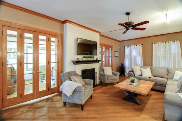 living room featuring french doors, ornamental molding, ceiling fan, and light hardwood / wood-style flooring