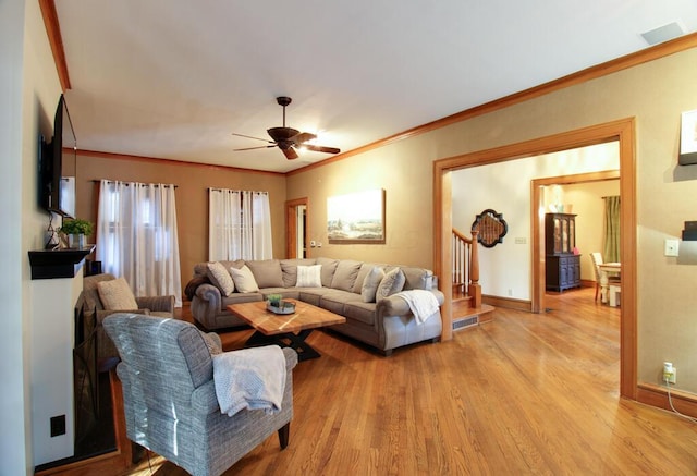 living room with crown molding, ceiling fan, and light wood-type flooring