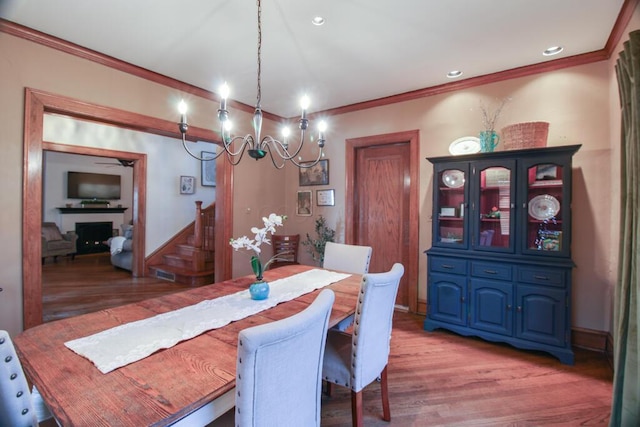 dining room featuring hardwood / wood-style flooring, a fireplace, and ornamental molding