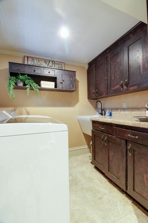 washroom featuring cabinets, ornamental molding, washer and clothes dryer, and sink