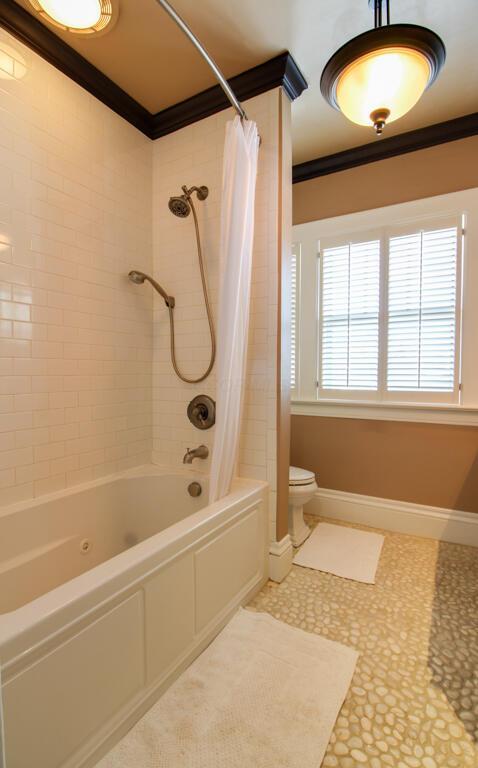 bathroom featuring crown molding, shower / bath combination with curtain, and toilet