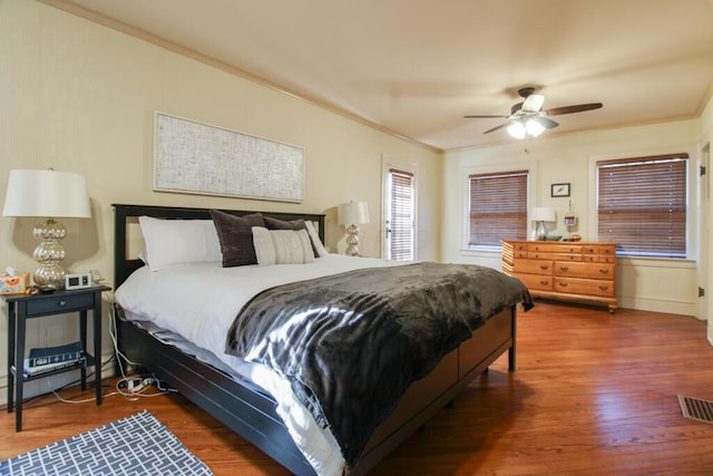 bedroom featuring crown molding, ceiling fan, dark wood-type flooring, and a baseboard heating unit