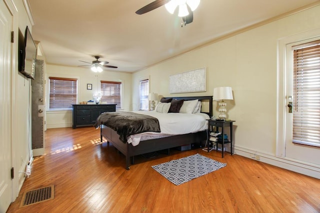 bedroom featuring wood-type flooring, ornamental molding, and ceiling fan