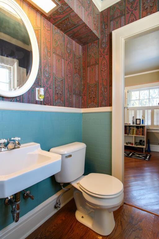 bathroom with sink, hardwood / wood-style flooring, crown molding, tile walls, and toilet