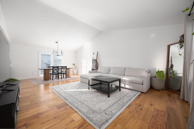 living room with light hardwood / wood-style floors, lofted ceiling, and a chandelier