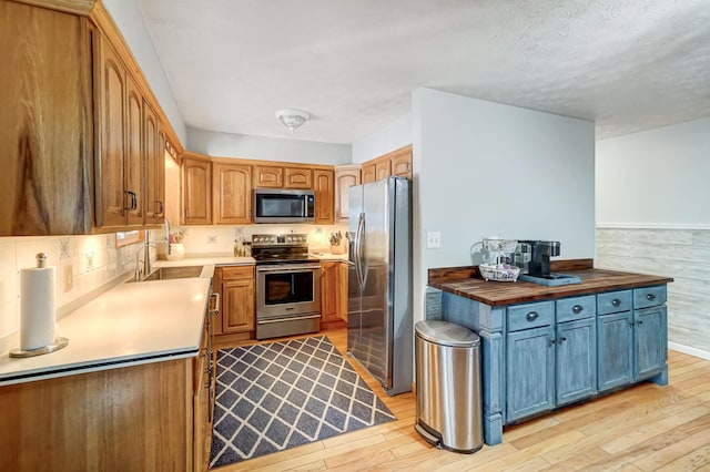 kitchen featuring stainless steel appliances, sink, butcher block counters, and light hardwood / wood-style floors