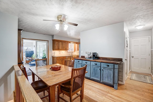 dining area featuring a textured ceiling, ceiling fan, and light wood-type flooring