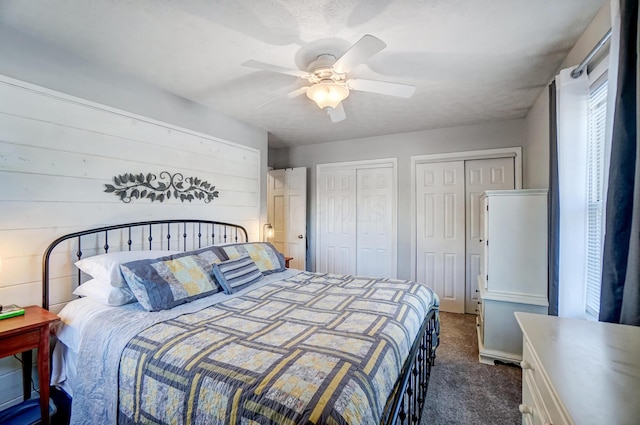 bedroom featuring ceiling fan, dark carpet, and multiple closets