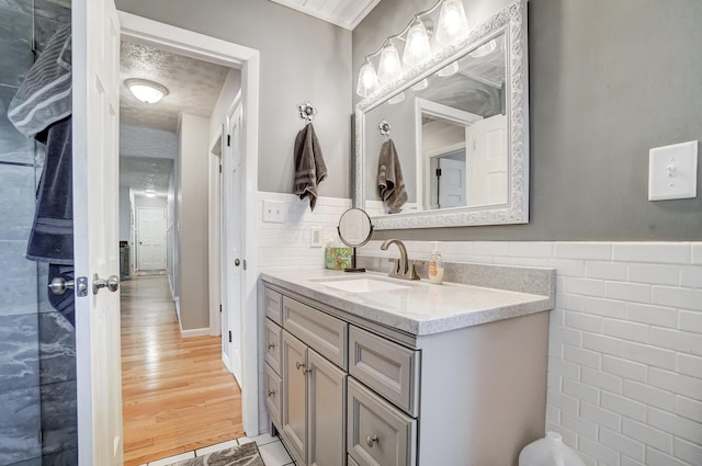 bathroom featuring hardwood / wood-style floors, vanity, tile walls, and a textured ceiling