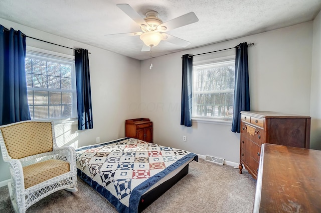 carpeted bedroom featuring ceiling fan and a textured ceiling