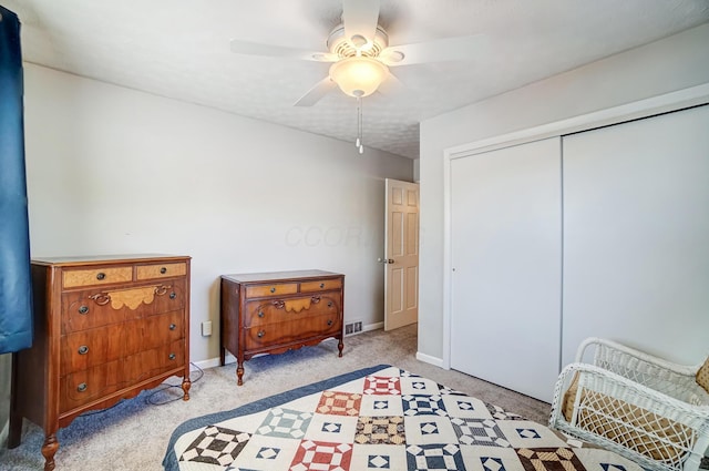 bedroom featuring light carpet, ceiling fan, and a closet