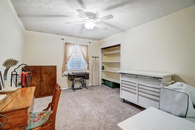 carpeted office featuring ceiling fan and a textured ceiling