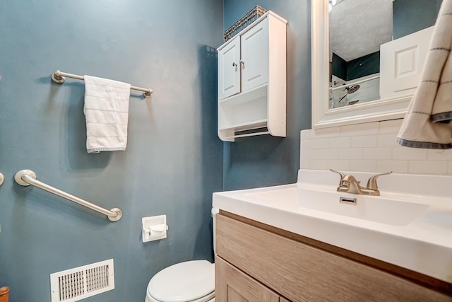 bathroom featuring vanity, backsplash, and toilet