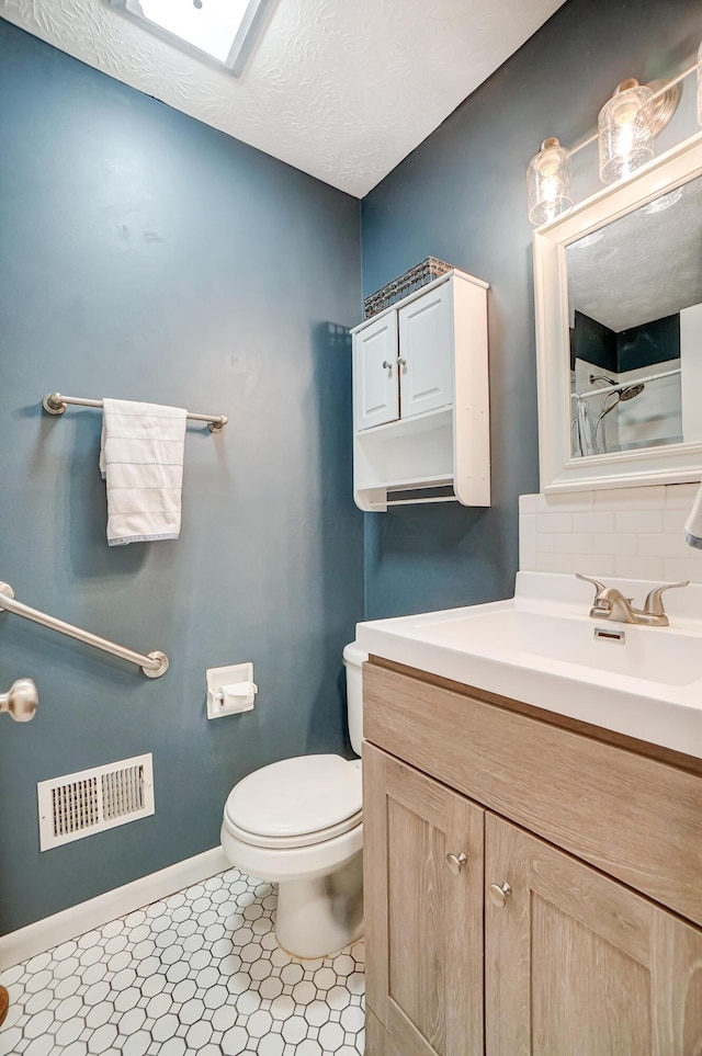 bathroom with vanity, backsplash, a textured ceiling, and toilet