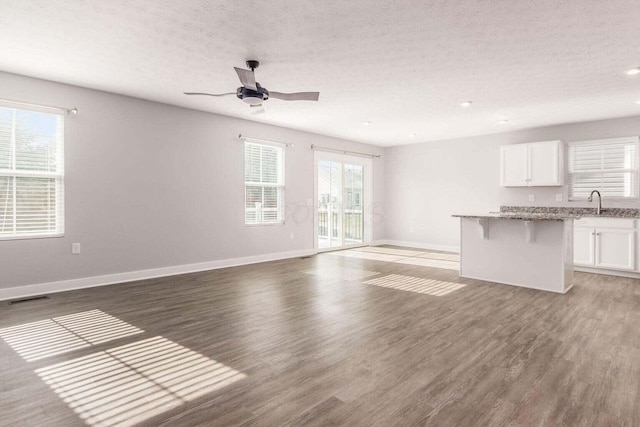 unfurnished living room with ceiling fan, dark wood-type flooring, a textured ceiling, and sink