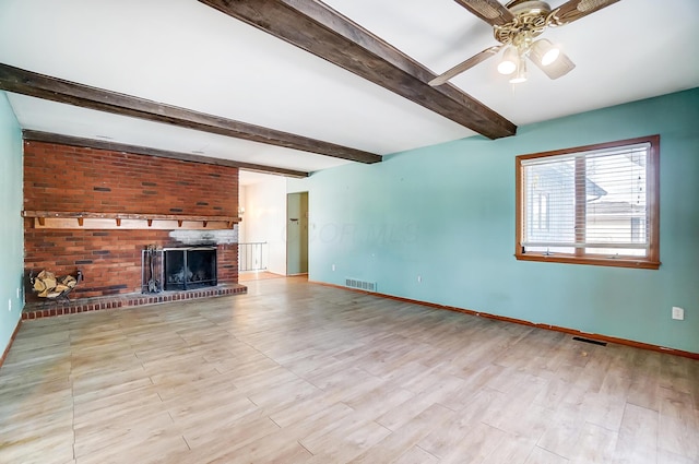 unfurnished living room featuring light hardwood / wood-style flooring, ceiling fan, a fireplace, and beamed ceiling