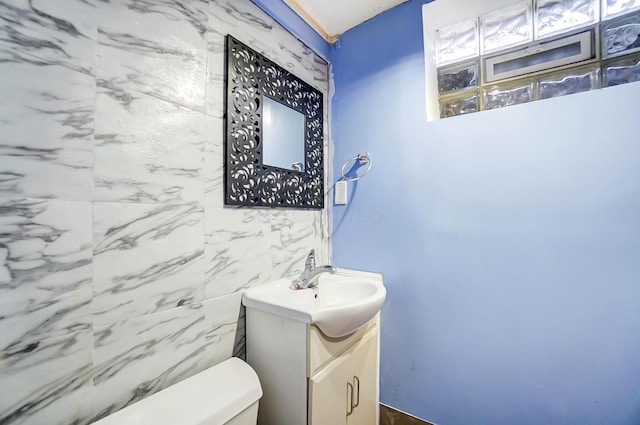 bathroom featuring vanity, tile walls, and toilet