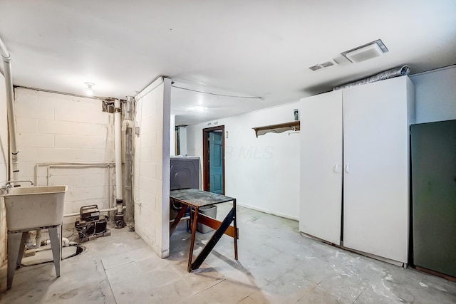 basement with sink, washer / dryer, and refrigerator