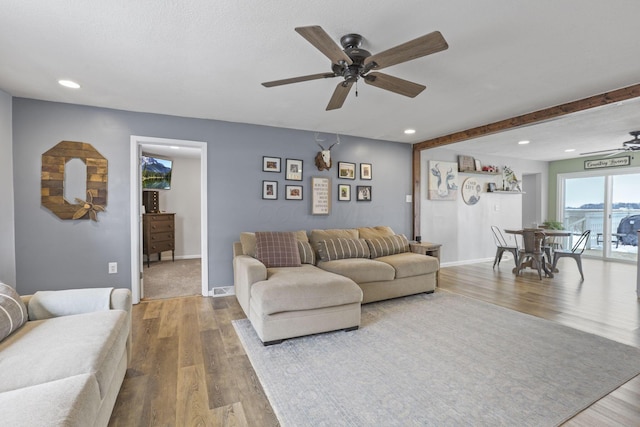 living room featuring hardwood / wood-style flooring, ceiling fan, and beamed ceiling