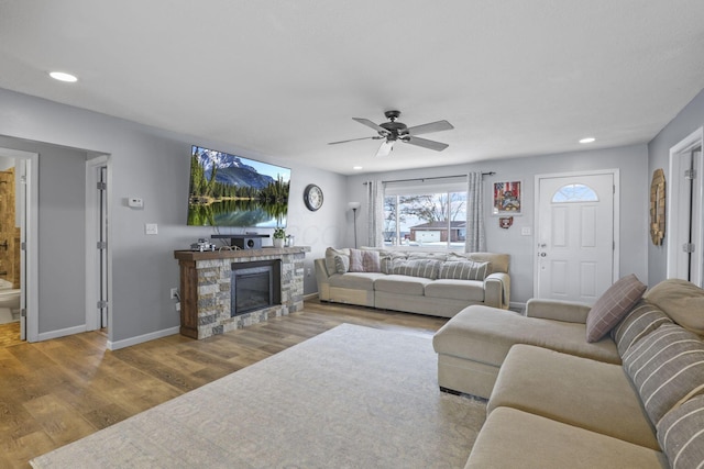 living room featuring hardwood / wood-style flooring, ceiling fan, and a fireplace