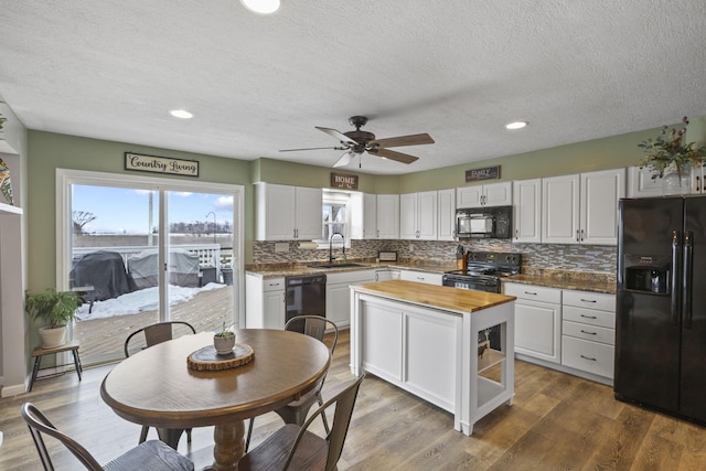 kitchen featuring dark hardwood / wood-style floors, butcher block countertops, sink, white cabinets, and black appliances