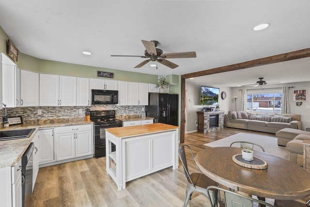 kitchen with sink, white cabinets, light hardwood / wood-style floors, black appliances, and beam ceiling