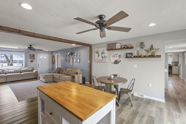 dining room featuring ceiling fan, beam ceiling, hardwood / wood-style floors, and a textured ceiling