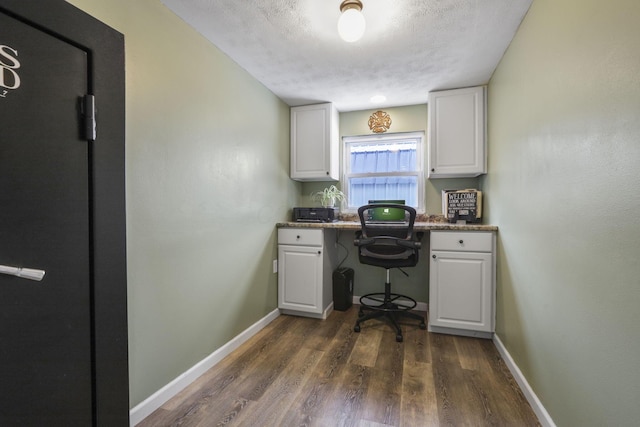 office area featuring dark hardwood / wood-style flooring, built in desk, and a textured ceiling