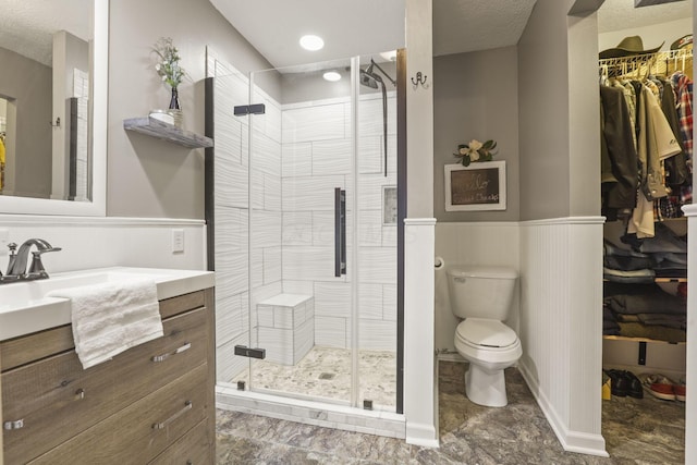 bathroom featuring vanity, a textured ceiling, a shower with door, and toilet