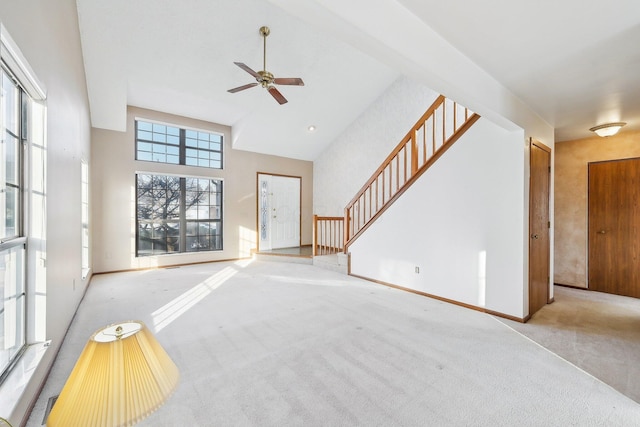 unfurnished living room featuring ceiling fan, a high ceiling, and light colored carpet