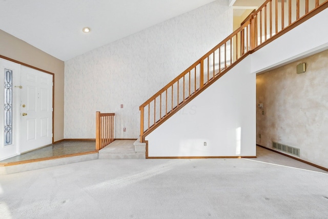 carpeted foyer featuring a high ceiling